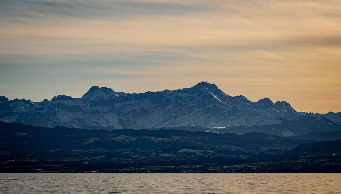 Schneebedeckte Berge mit sanften Hügeln im Vordergrund und bewölktem Himmel.